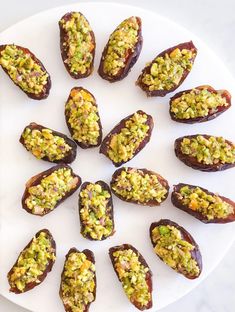 a white plate topped with stuffed dates covered in pistachio