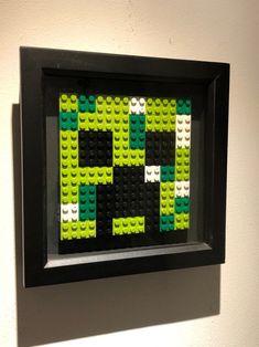 a black frame with green and white legos in it on the wall next to a light switch