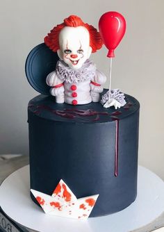 there is a cake with a clown on it and a red balloon in the air