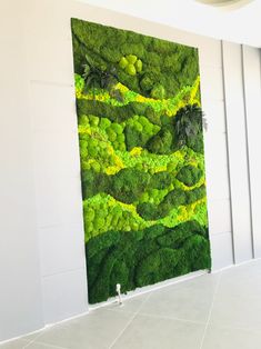 a large green wall hanging on the side of a building with white walls and tile flooring