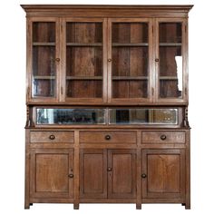 an old wooden china cabinet with glass doors on the top and bottom shelf, in front of a white background