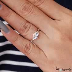 a woman's hand with a ring on her finger and an oval shaped diamond in the middle