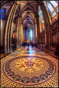 the inside of an old cathedral with stained glass windows and intricate mosaic tile flooring