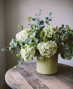 a vase filled with green flowers sitting on top of a wooden table