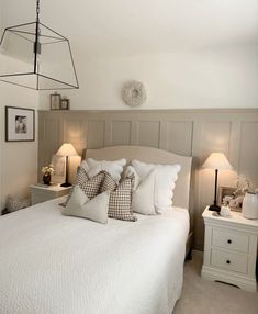 a white bed sitting next to two lamps on either side of the headboard and foot board