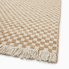 a beige and white checkered rug with fringes