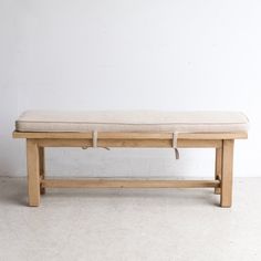 a wooden bench sitting on top of a white floor next to a wall with no one in it