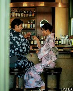 two people in kimonos sitting at a bar