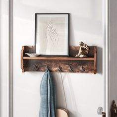 a wooden shelf with coat hooks on it and a framed picture hanging over the top