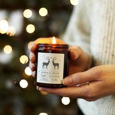 a person holding a candle in front of a christmas tree