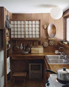 a kitchen with wooden walls and flooring next to a stove top oven under a hanging light