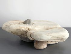 a rock sitting on top of a wooden bench next to a white wall and gray floor