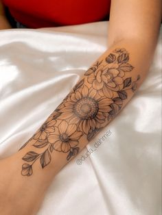 a woman's arm with flowers and leaves on it