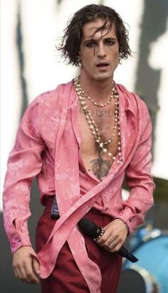 a man in pink shirt and pearl necklace on stage