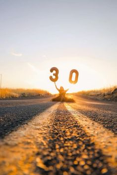 the number 30 is written in the middle of an empty road as the sun sets