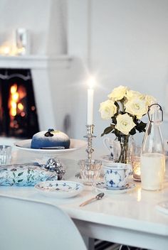 a white table topped with plates covered in cake next to a fire place filled with candles