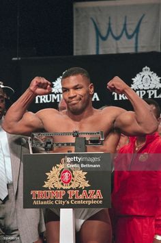 professional wrestler posing for the camera with his arms in the air as he stands behind a podium