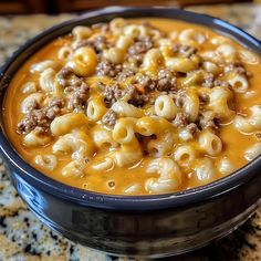 a bowl filled with macaroni and cheese soup on top of a granite counter