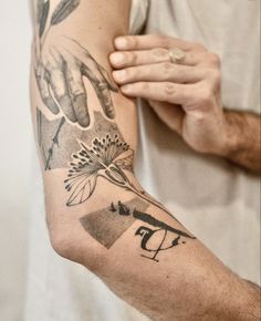 a man holding his arm with tattoos on it