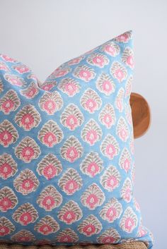 a blue and pink pillow sitting on top of a wooden chair