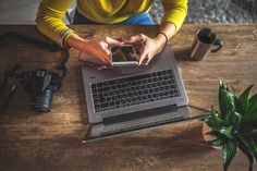 a woman sitting at a table with a laptop and cell phone in front of her