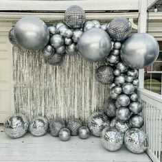 a bunch of balloons that are in front of a wall with silver balls on it