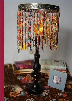 a lamp that is on top of a table with some beads hanging from the lampshade