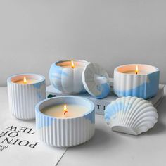 three candles sitting next to each other on top of a book with seashells