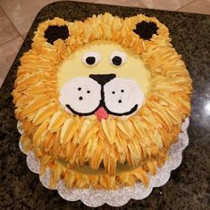 a lion cake with yellow icing and black eyes on a granite countertopstop