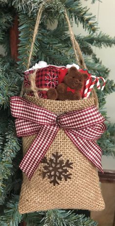 a christmas ornament hanging from a tree with a teddy bear in the bag