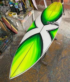 the surfboard is painted green and white with an abstract design on it's side