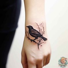 a small black bird tattoo on the wrist