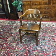 a wooden chair sitting on top of a rug in front of a dresser and other furniture