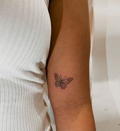 a woman's arm with a small butterfly tattoo on the left side of her arm