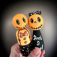 two handmade pumpkins with faces painted on them are held in front of the camera