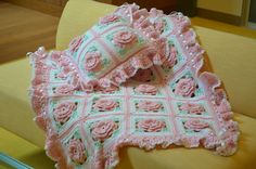 a crocheted blanket with pink flowers on it sitting on top of a chair