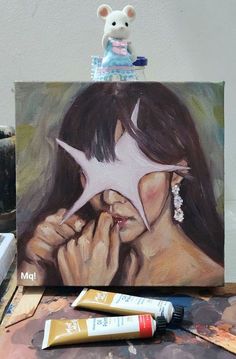 a painting of a woman with a star on her face next to some paint tubes