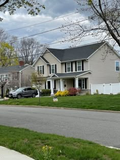 a car parked in front of a two story house on the side of a road