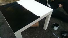 a white table sitting on top of a wooden floor next to a black and white chair