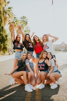 a group of young women standing next to each other in the middle of a road