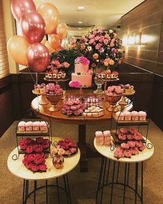 a table topped with cakes and cupcakes next to pink flowers in vases