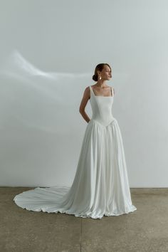 a woman in a white dress is standing on the concrete floor with her hands on her hips