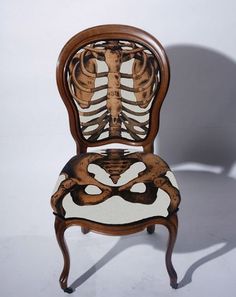 a skeleton sitting on top of a wooden chair next to a white wall and floor