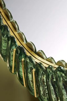 a mirror that has some green glass on top of it and gold trim around the edge