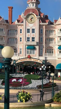 a large building with a clock on it's face in front of a fountain