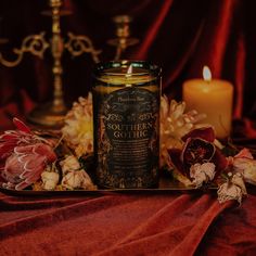 a candle sitting on top of a table next to some flowers and other things in front of it