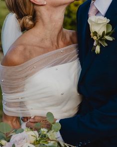 a bride and groom kissing each other outside