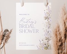 a bridal shower sign hanging on a wall next to dried flowers and pamodia