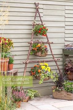 an outdoor garden with flowers and plants in baskets on the side of a house wall