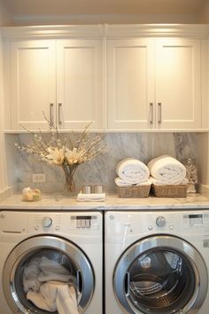 a washer and dryer in a white laundry room with marble counter tops on the wall